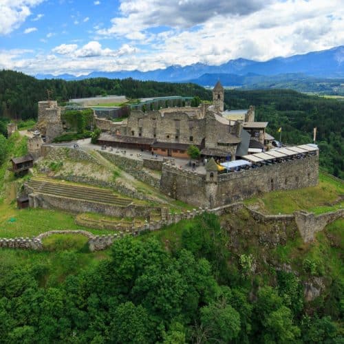 Ausflug zu Adlerarena Burg Landskron - Luftaufnahme mit Burgruine und Mittagskogel - Karawanken im Hintergrund