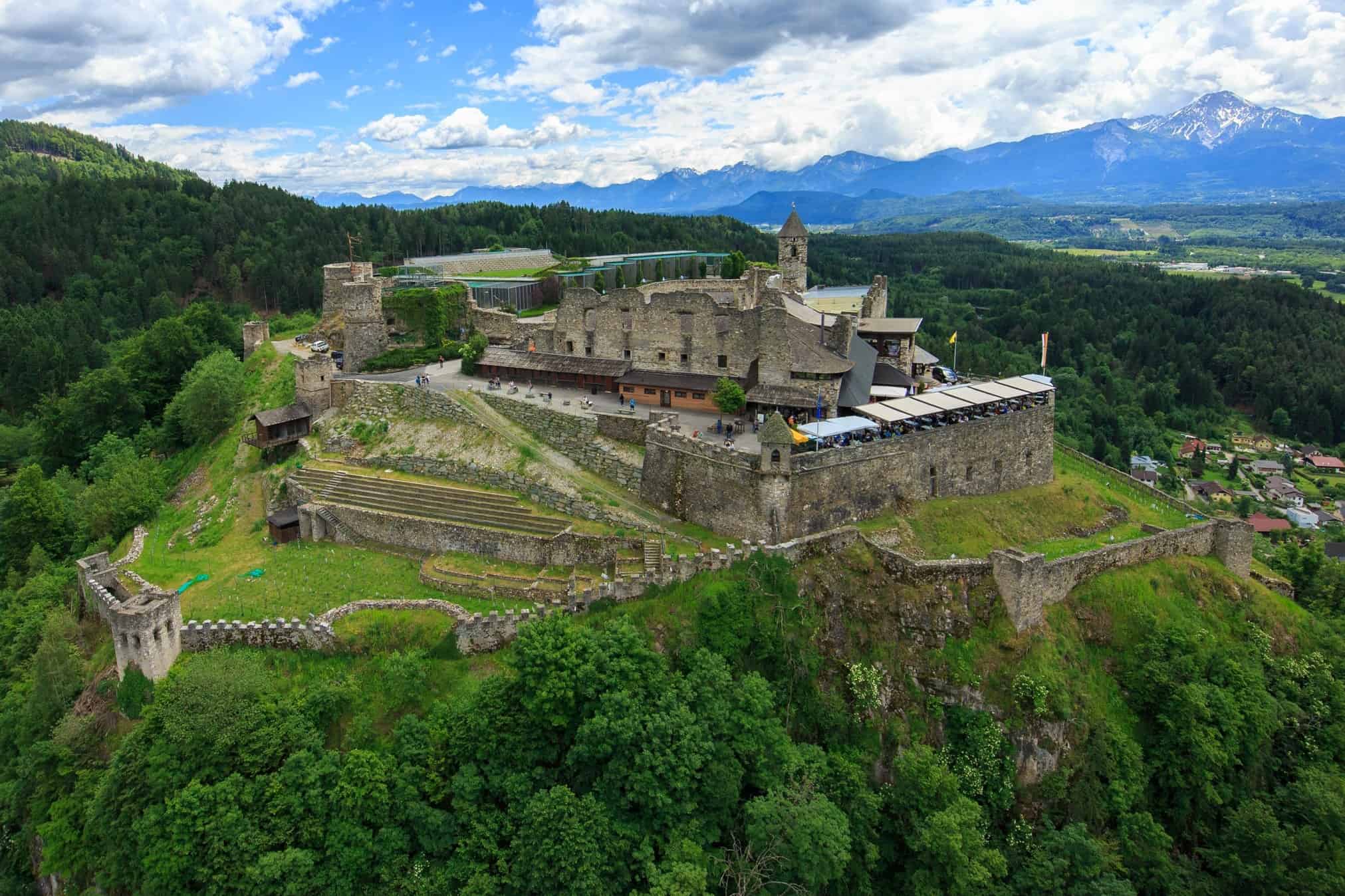 Ausflug zu Adlerarena Burg Landskron - Luftaufnahme mit Burgruine und Mittagskogel - Karawanken im Hintergrund