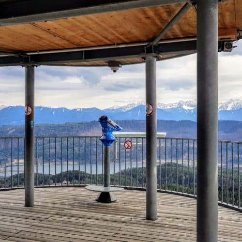 Aussichtsplattform am Pyramidenkogel in Kärnten. Blick auf Keutschacher See und Karawanken. Fernrohr auf Plattform.