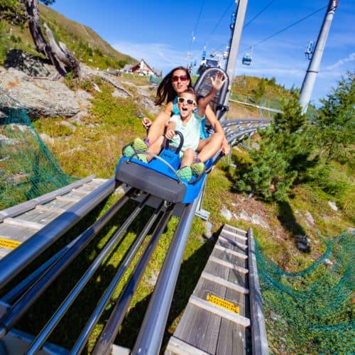 Erwachsene und Kind auf der Sommerrodelbahn Nocky Flitzer auf der Turracher Höhe in Kärnten