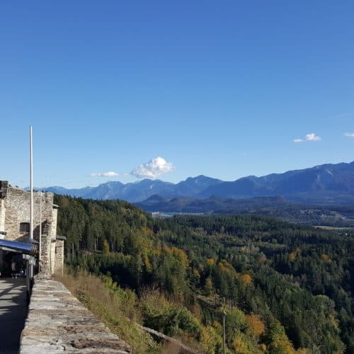 Aussicht auf Karawanken von der Adlerarena Burg Landskron Kärnten. Kind blickt durch Fernrohr