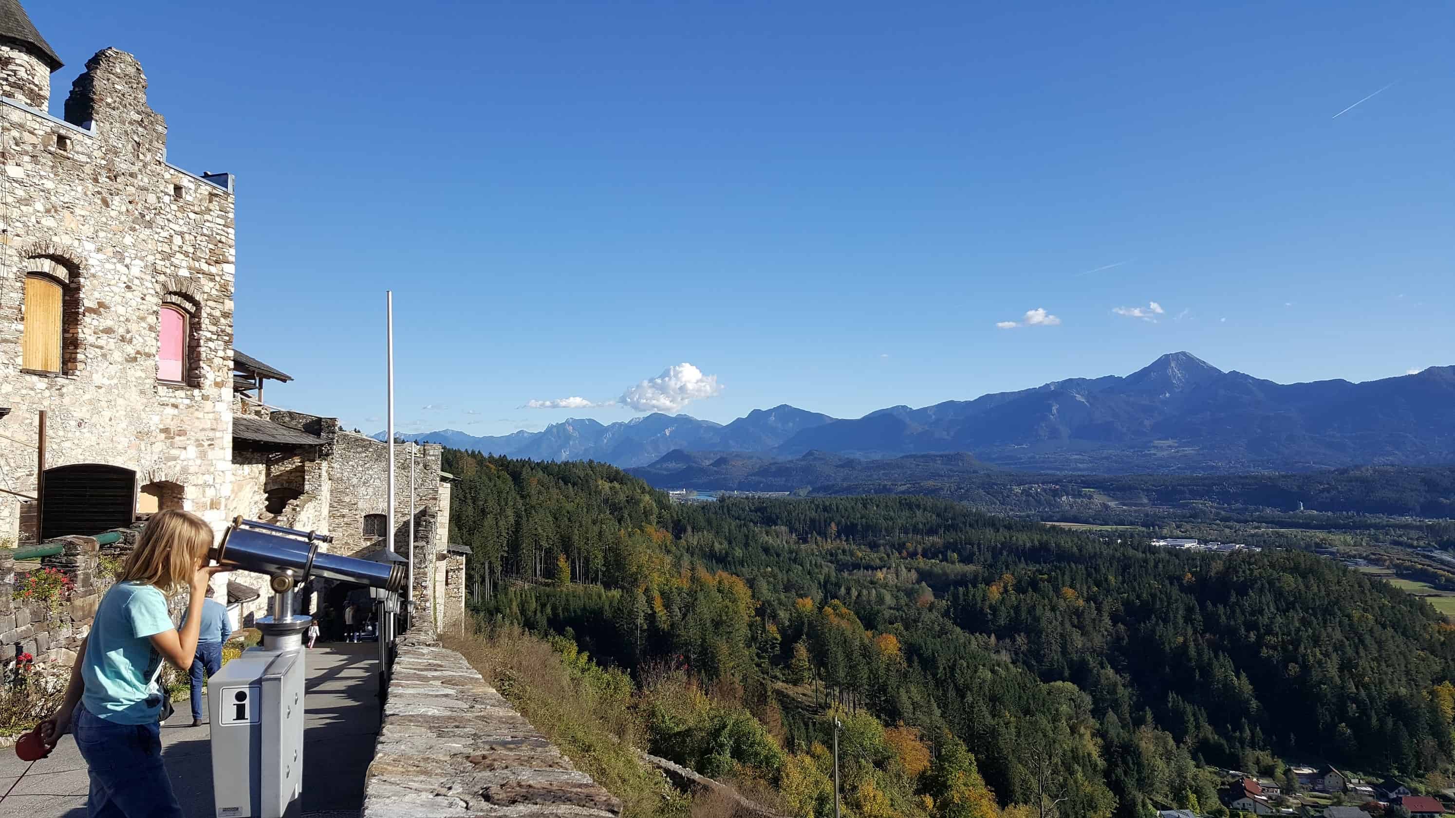 Aussicht auf Karawanken von der Adlerarena Burg Landskron Kärnten. Kind blickt durch Fernrohr