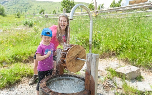 Spielende Familie am Wasserspielplatz in der Kindererlebniswelt Nocky's Almzeit auf der Turracher Höhe - Österreich