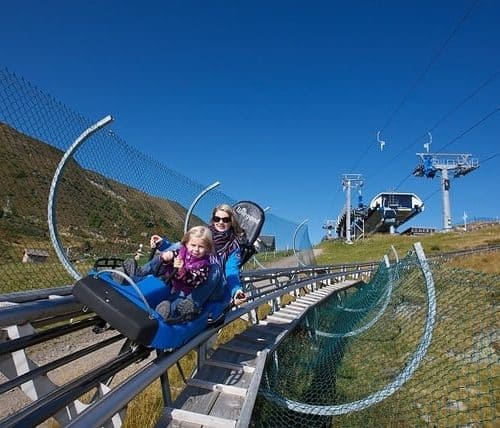 Sommer Rodelbahn Nocky Flitzer auf der Turracher Höhe in Kärnten. Erwachsene mit Kind auf der rasanten Attraktion.