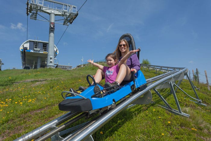 Kind mit Eltern auf der Sommerrodelbahn Nocky Flitzer auf der Turracher Höhe in Kärnten und Steiermark in Österreich