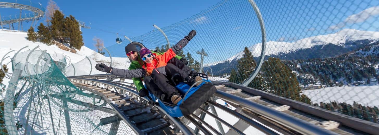 Nocky Flitzer Turracher Höhe Rodelbahn TOP 10 Ausflugsziele Kärnten Steiermark im Winter. Vater mit Kind beim Rodeln.