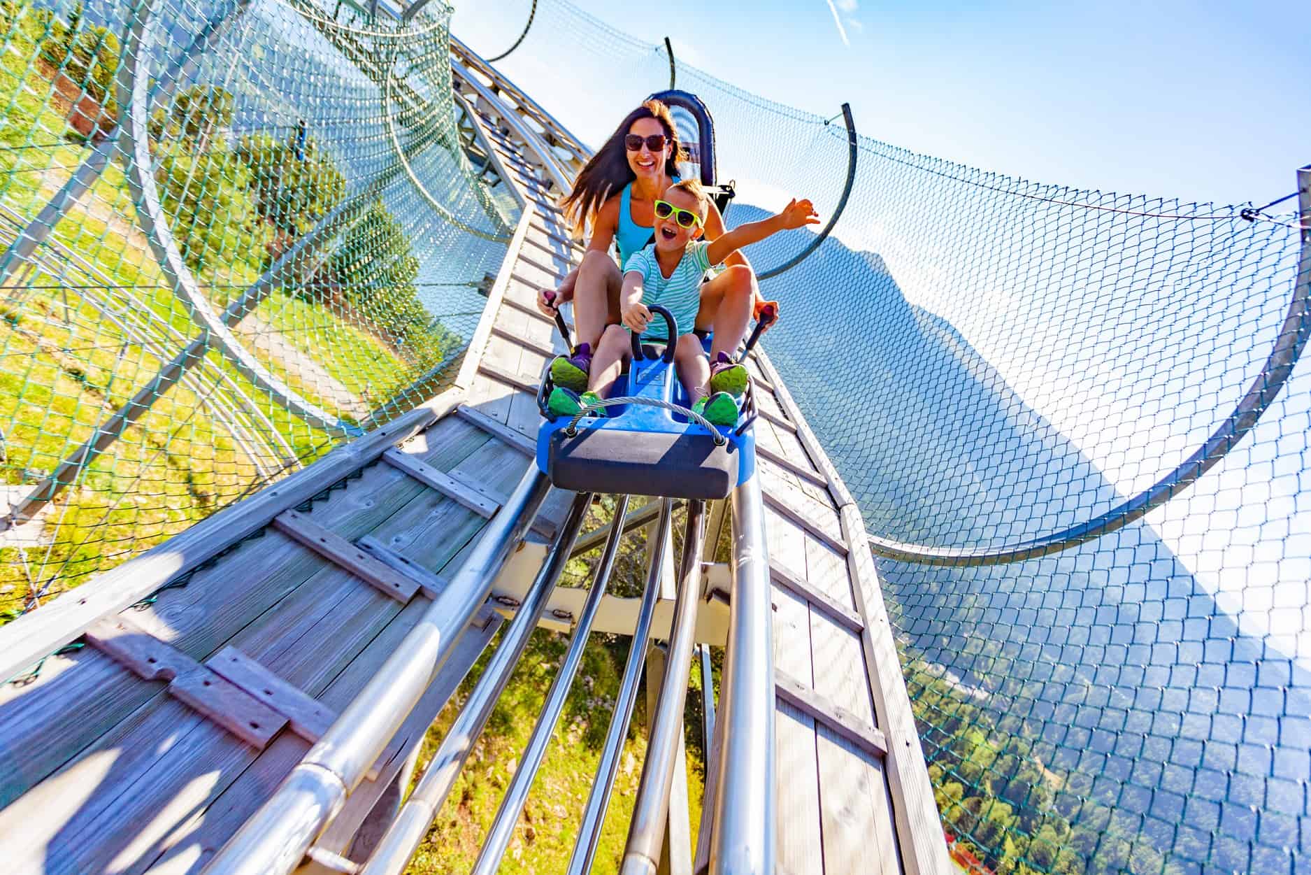 Auf der Alpen-Rodelbahn Nocky Flitzer auf der Turracher Höhe in Kärnten. Erwachsene mit Kind flitzen vom Berg ins Tal.