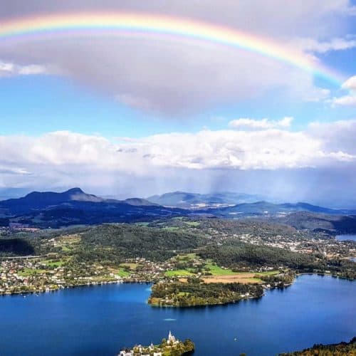 Regenbogen über Wörthersee bei Ausflug auf Pyramidenkogel. Blick auf Klagenfurt, Maria Wörth, Krumpendorf und Pörtschach. Sehenswürdigkeit in Österreich.