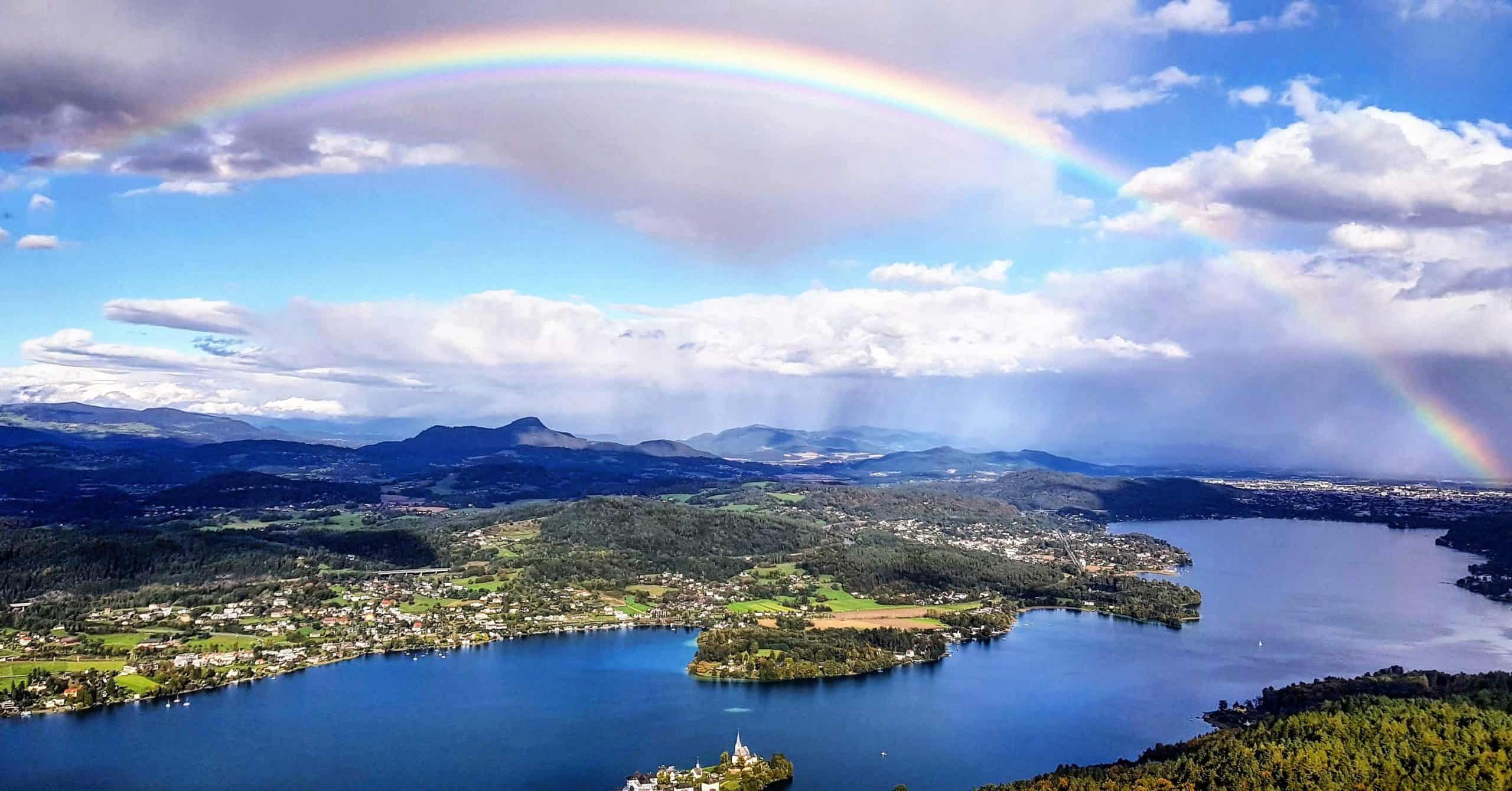 Regenbogen über Wörthersee bei Ausflug auf Pyramidenkogel. Blick auf Klagenfurt, Maria Wörth, Krumpendorf und Pörtschach. Sehenswürdigkeit in Österreich.