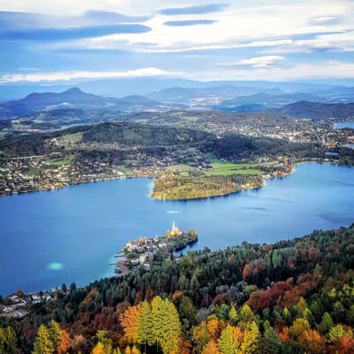 Traumhafter Blick auf Maria Wörth vom Pyramidenkogel in Kärnten am Wörthersee bei Herbsturlaub. Blätter sind bereits bunt.