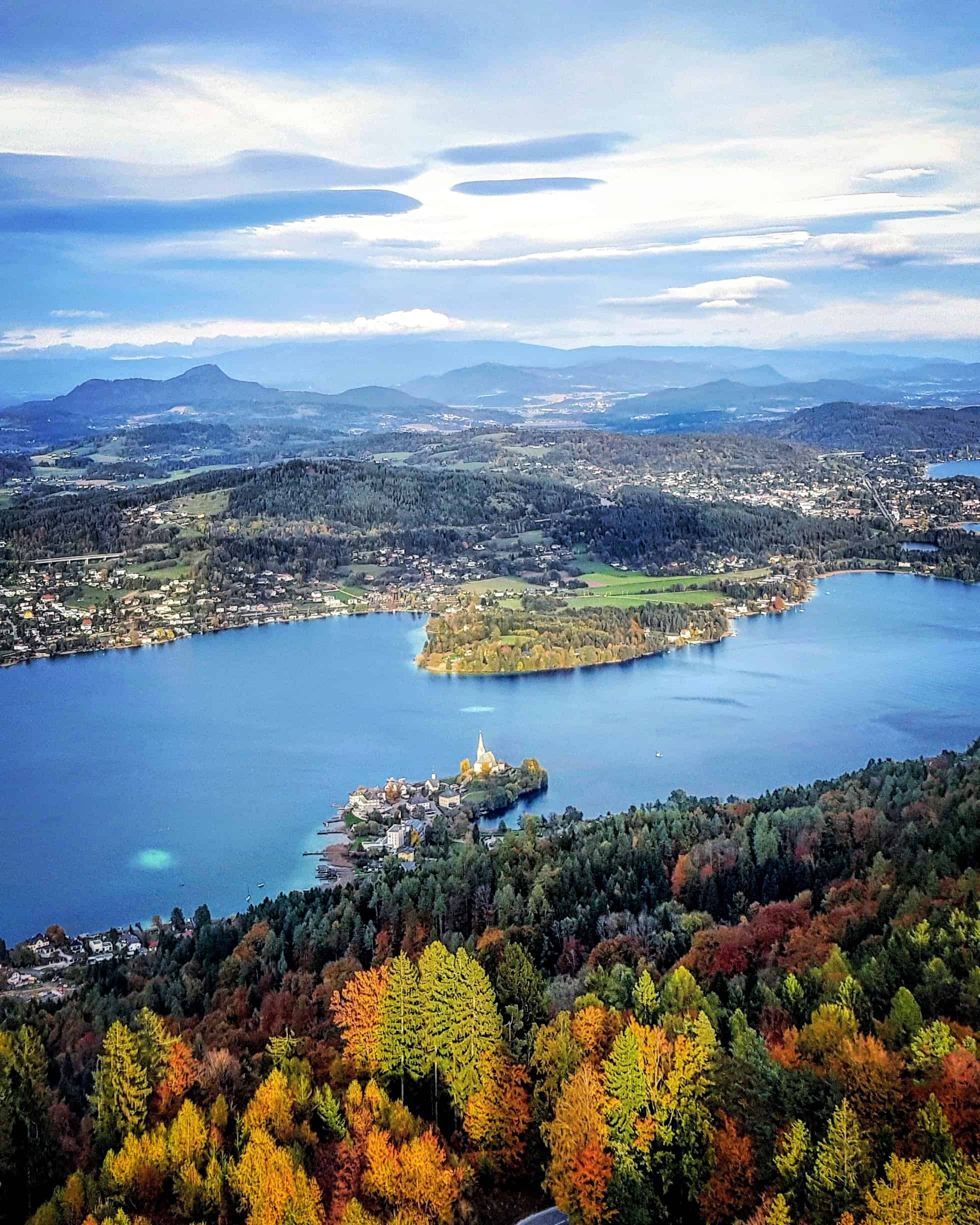 Traumhafter Blick auf Maria Wörth vom Pyramidenkogel in Kärnten am Wörthersee bei Herbsturlaub. Blätter sind bereits bunt.