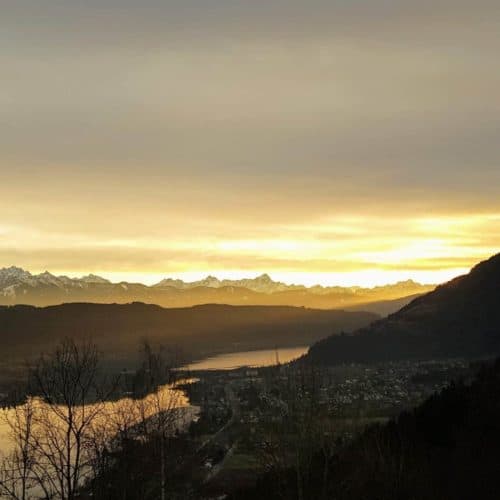 Panorama mit Sonnenuntergang am Wanderweg über den Ossiacher See und Steindorf in der Region Villach in Kärnten, Österreich.