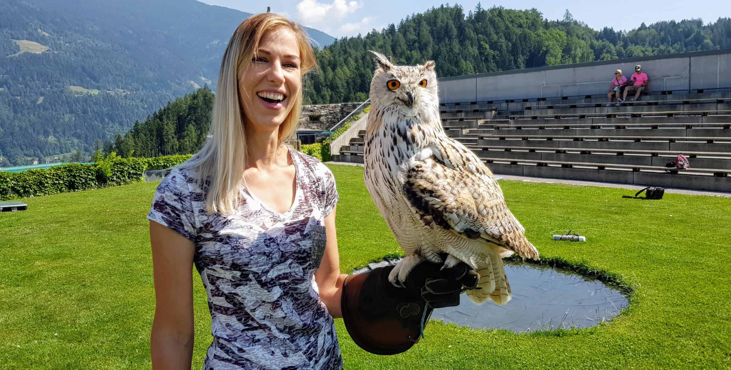 Sibirischer Uhu mit Besucherin auf der Adlerarena Burg Landskron in Kärnten am Ossiacher See bei Urlaub in Villach, Österreich