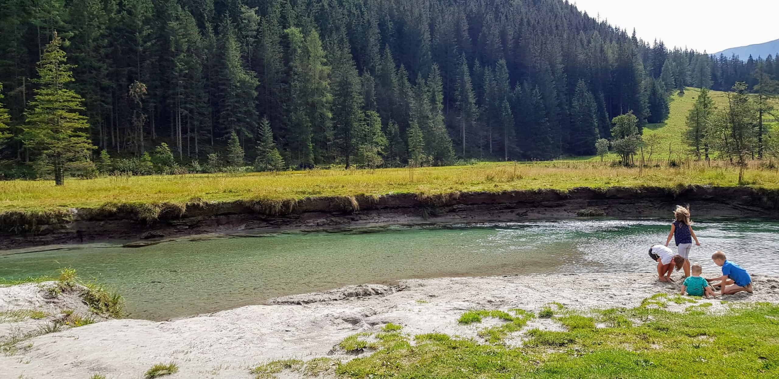 Kinder spielen am Fluss bei Erlebnisspielplatz Freizeitpark Mallnitz bei Ankogel Bergbahn im Nationalpark Hohe Tauern. Tipp für Kärnten mit Kindern. Eintritt frei.