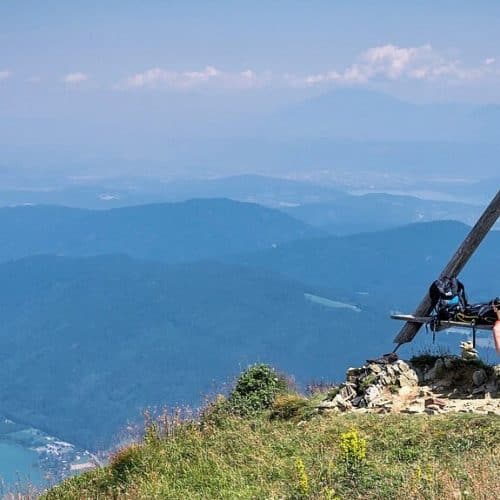 Geheimtipps & schöne Orte in Kärnten: Wanderer auf der Gerlitzen Alpe mit Blick auf Ossiacher See, Bleistätter Moor & Karawanken